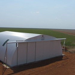 Vista geral do galpão Omega+ com portas fechadas, aeronave estacionada ao lado.