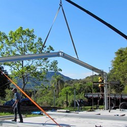um caminhão guindaste levanta e posiciona o primeiro pórtico