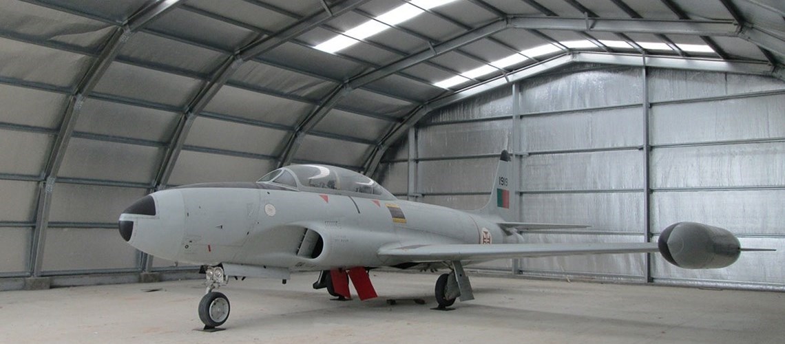 vista interior de um galpão Omega+ usado para guardar um avião antigo em museu de aviação